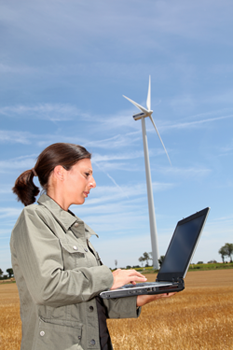 Woman with computer in front of wind turbine