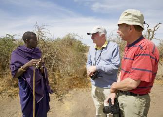 Two anthropologists talk to man in a desert environment.