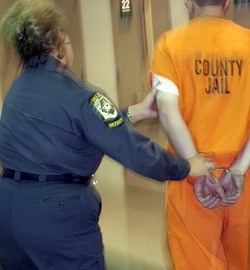 Correctional officer walking an inmate down a hallway