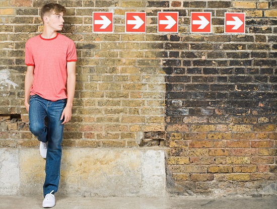 Young man standing against a wall with arrows