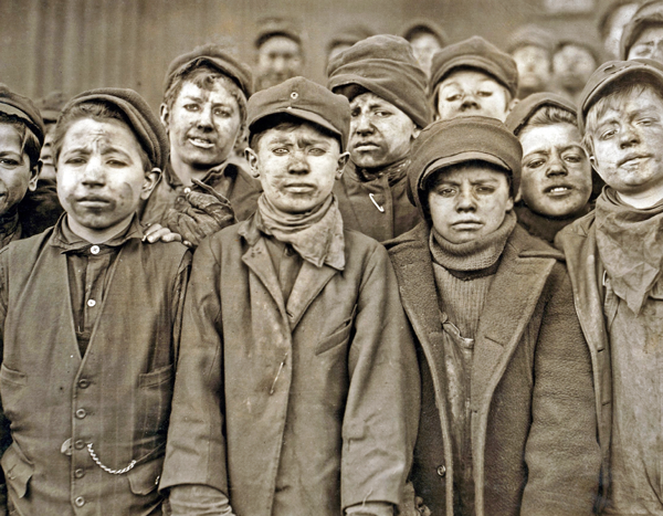 Dust-covered breaker boys at Pennsylvania Coal mine used hammers to “clean” the coal, separating slate rock from the mined coal. Photo by Lewis Hine, 1911. Copyright: Everett Historical.